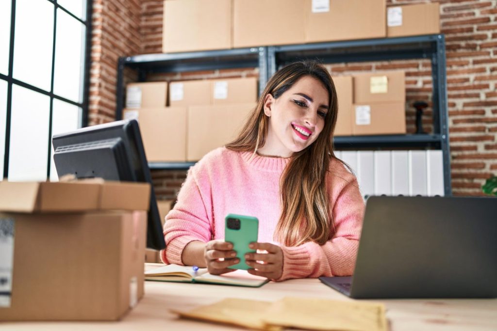 trabalhadora de negocios de comercio eletronico jovem e bonita mulher hispanica usando smartphone no escritorio.jpg
